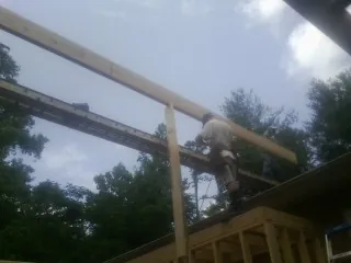 Carpenter setting a ridge beam over a new addition frame — Ice Dam Removal by Roofing Brothers in Malden