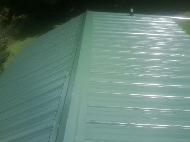 New green metal panels meeting at the ridge of a roof — Flat Roof Repair work by our crew in Malden