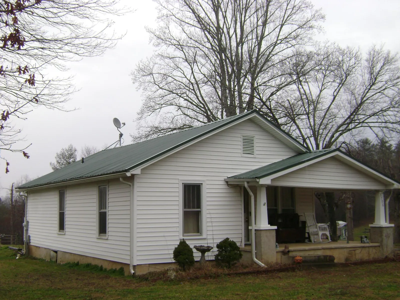 Green metal roof on a white bungalow with a side porch in Malden