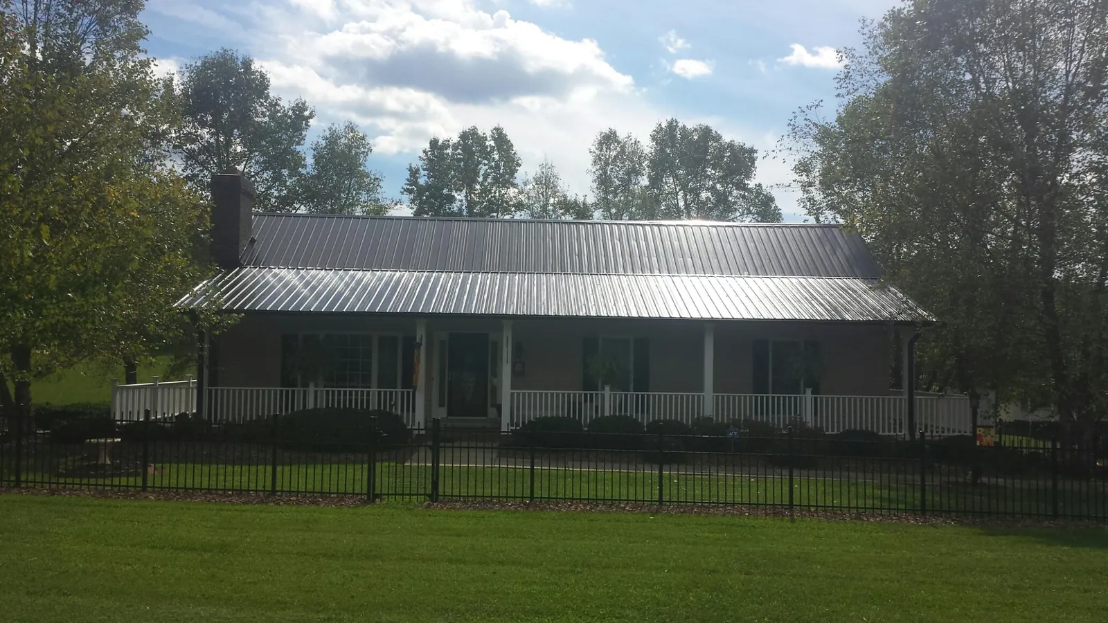 Gray metal roof on a brick ranch with a full width front porch — Gutter Guard Installation work by our crew in Malden